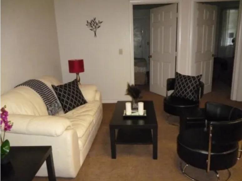 Living room with sofa, chairs and view to bedrooms